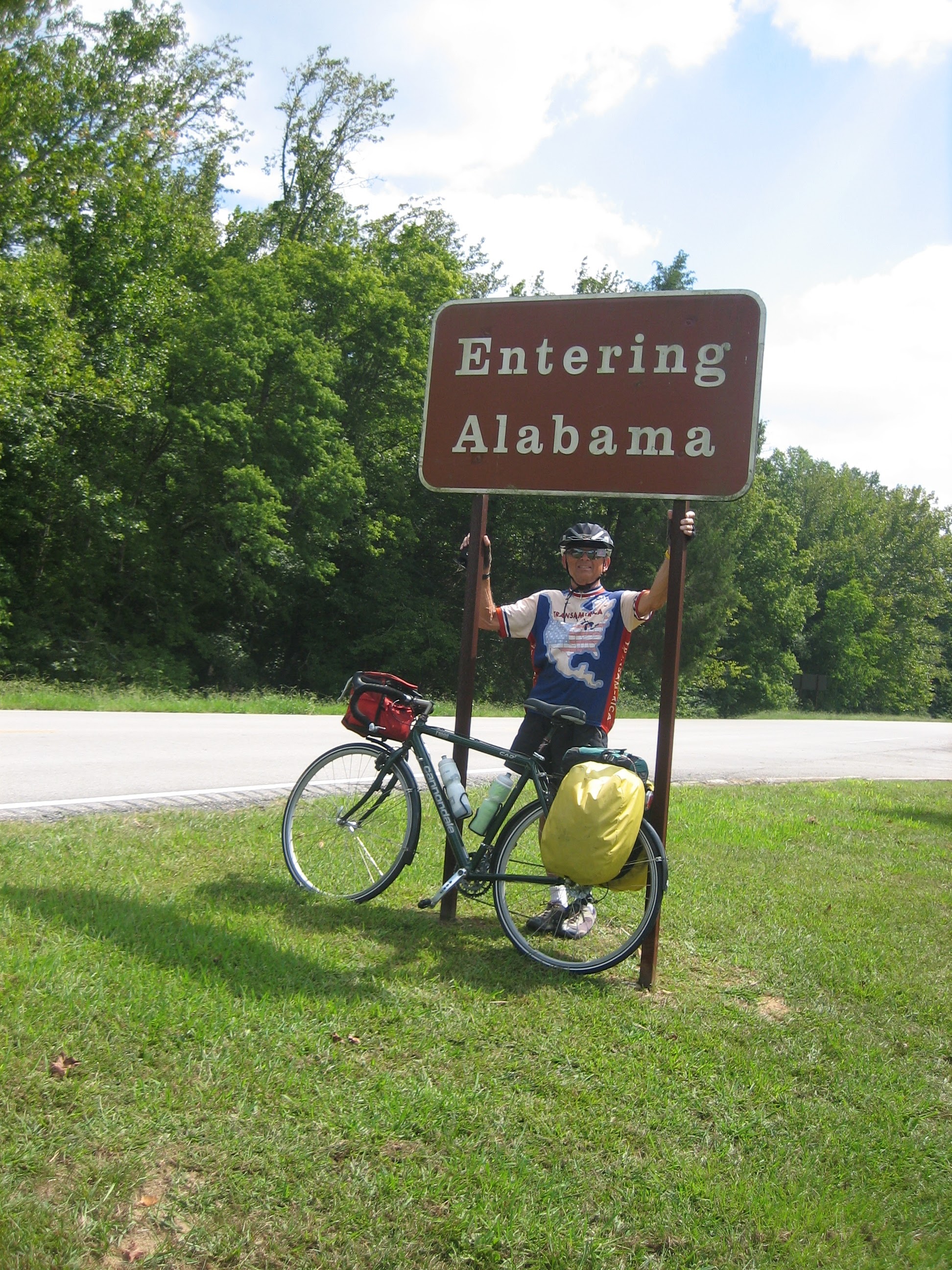 Tom or his touring bicycle photographed at the Alabama state line or state landmark.
