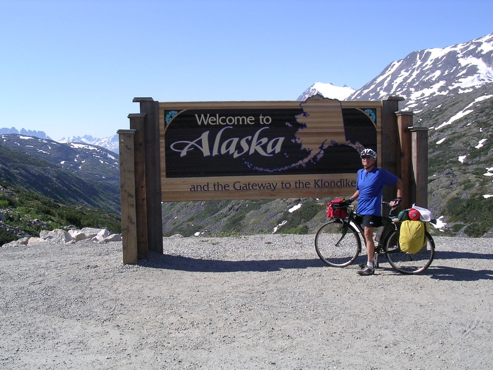 Tom or his touring bicycle photographed at the Alaska state line or state landmark.