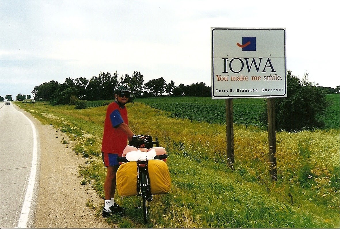 Tom or his touring bicycle photographed at the Iowa state line or state landmark.