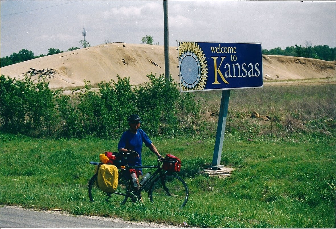 Tom or his touring bicycle photographed at the Kansas state line or state landmark.