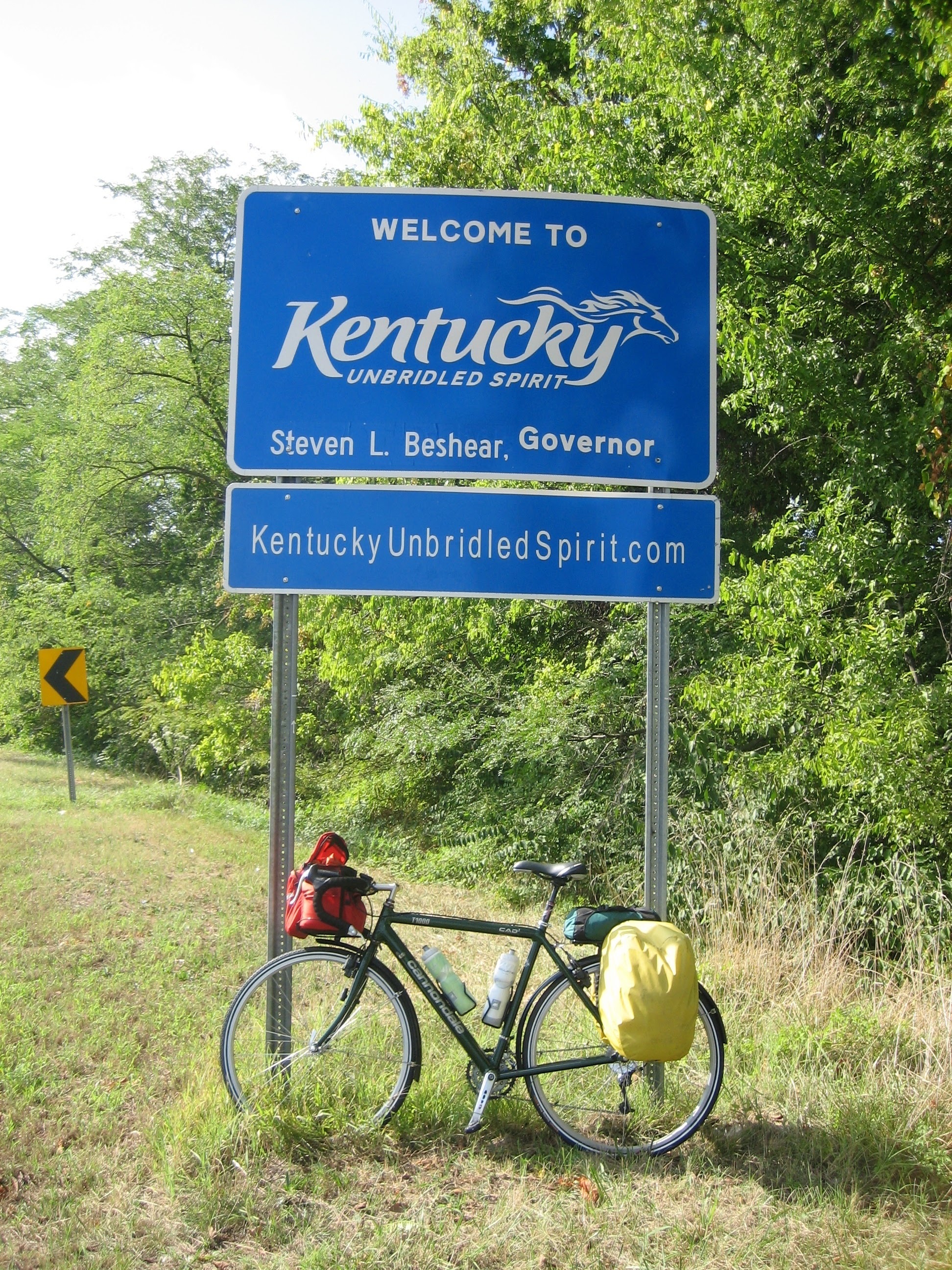 Tom or his touring bicycle photographed at the Kentucky state line or state landmark.