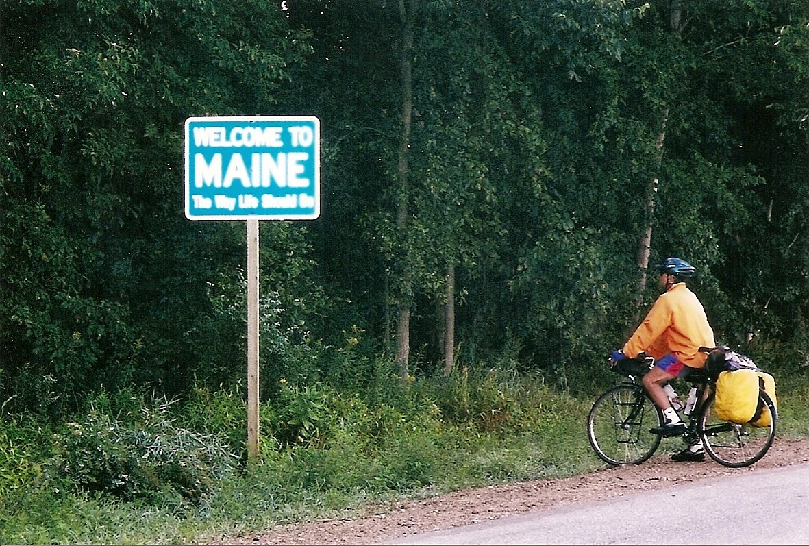 Tom or his touring bicycle photographed at the Maine state line or state landmark.