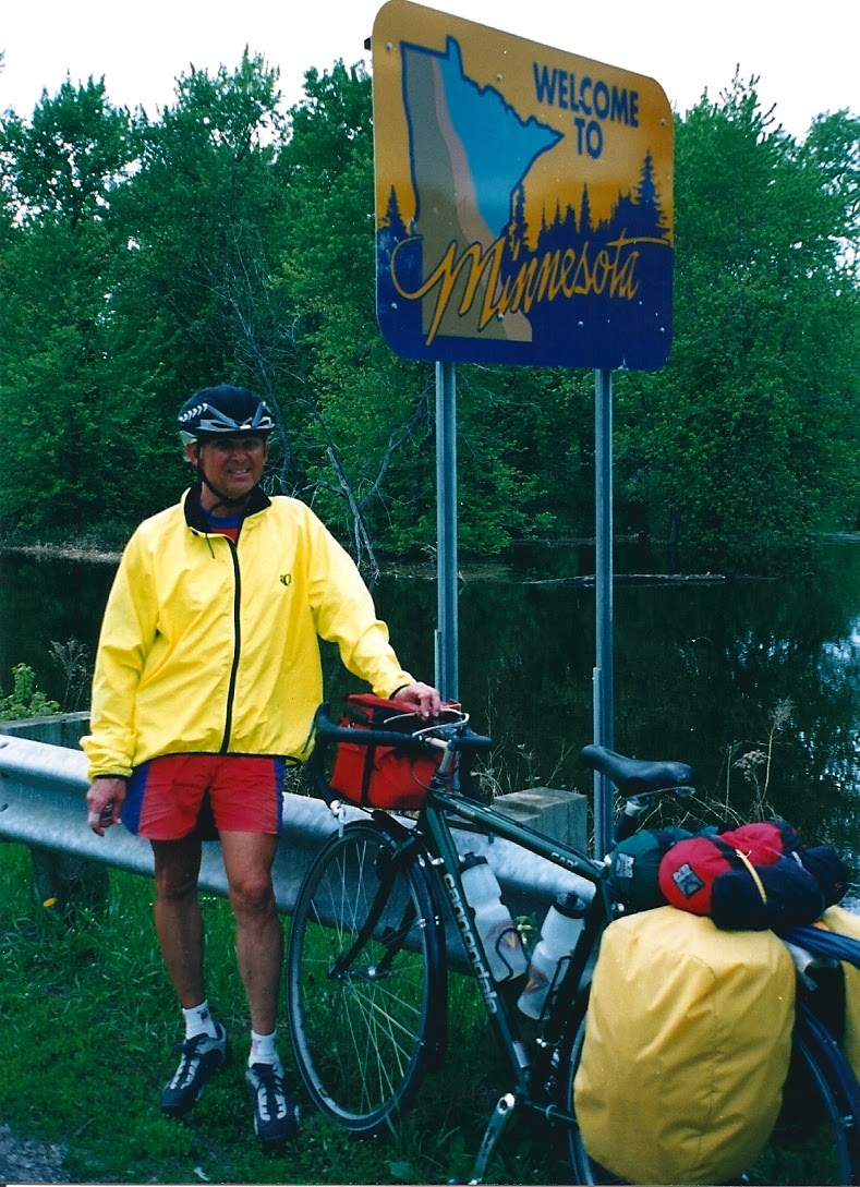 Tom or his touring bicycle photographed at the Minnesota state line or state landmark.