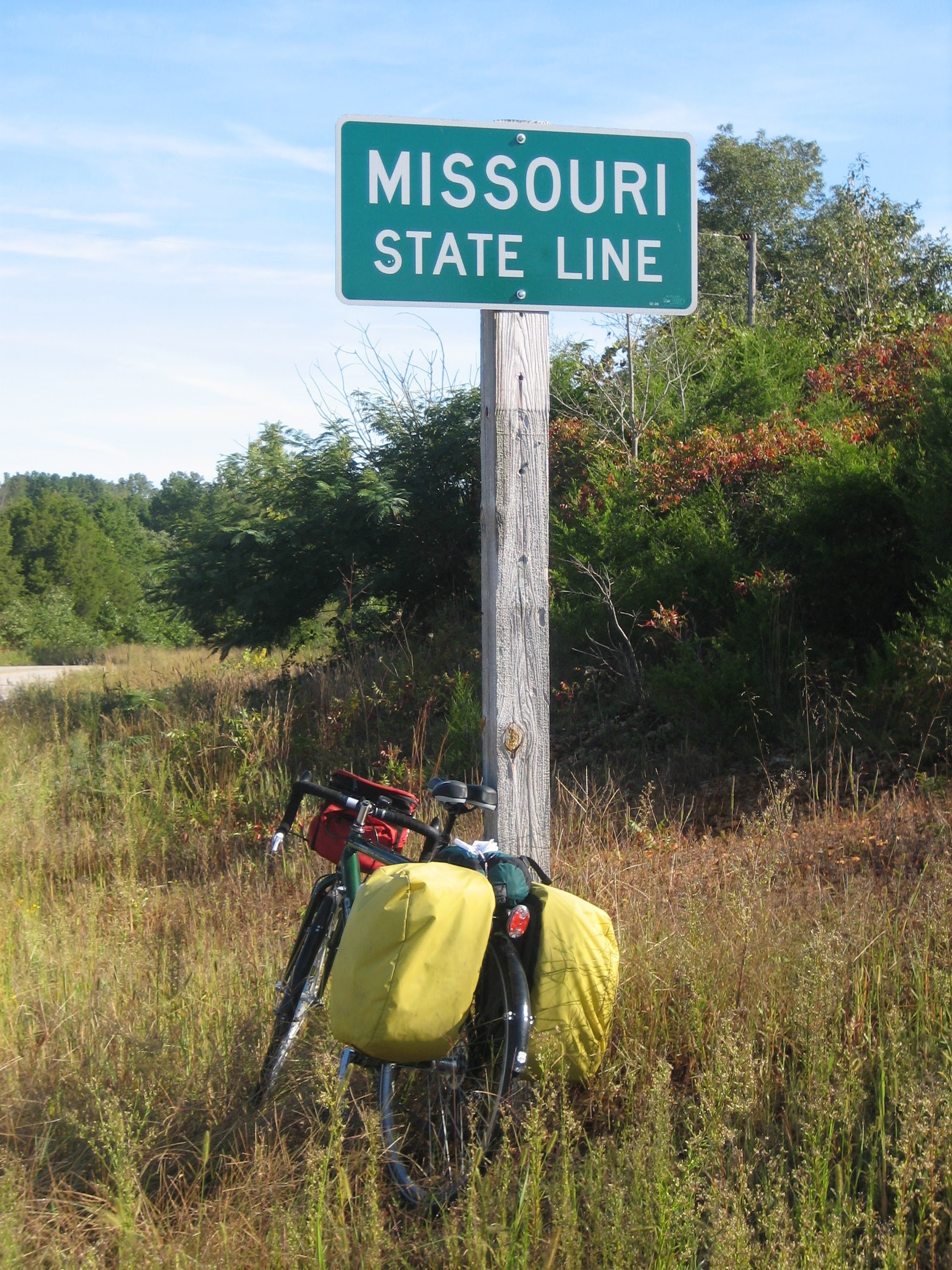 Tom or his touring bicycle photographed at the Missouri state line or state landmark.