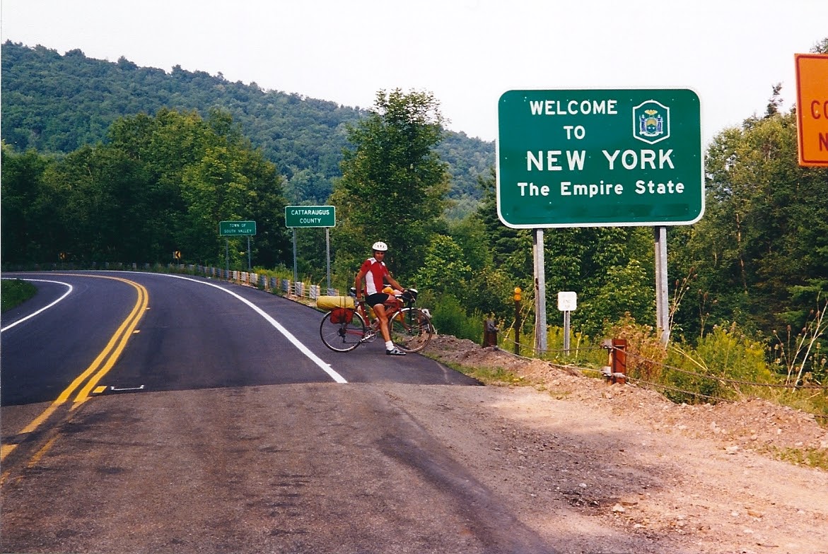 Tom or his touring bicycle photographed at the New York state line or state landmark.
