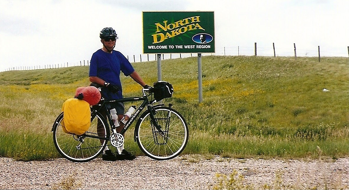 Tom or his touring bicycle photographed at the North Dakota state line or state landmark.