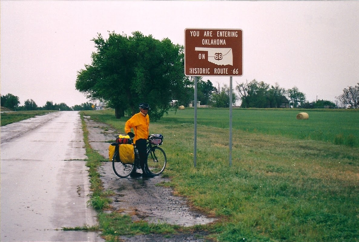 Tom or his touring bicycle photographed at the Oklahoma state line or state landmark.