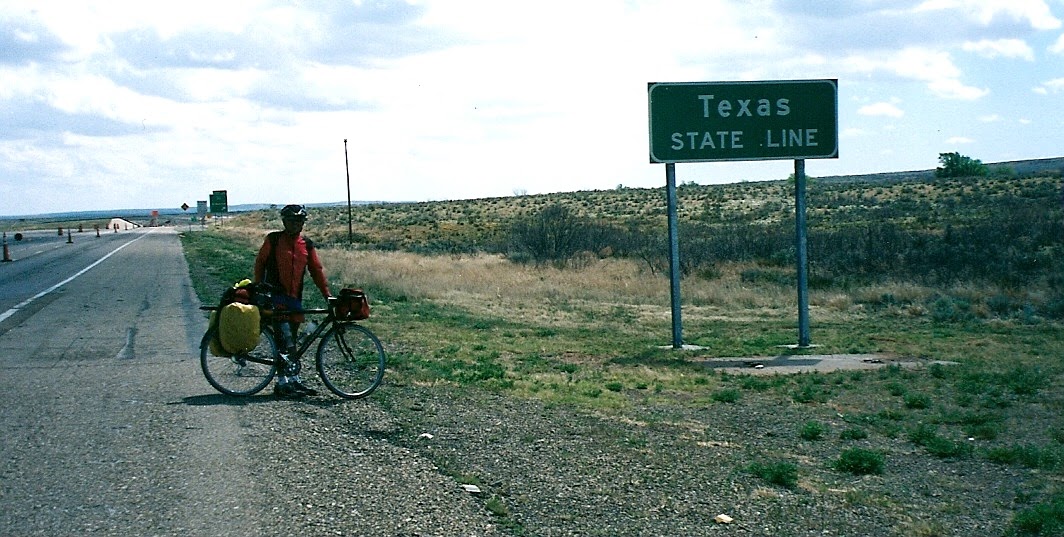 Tom or his touring bicycle photographed at the Texas state line or state landmark.