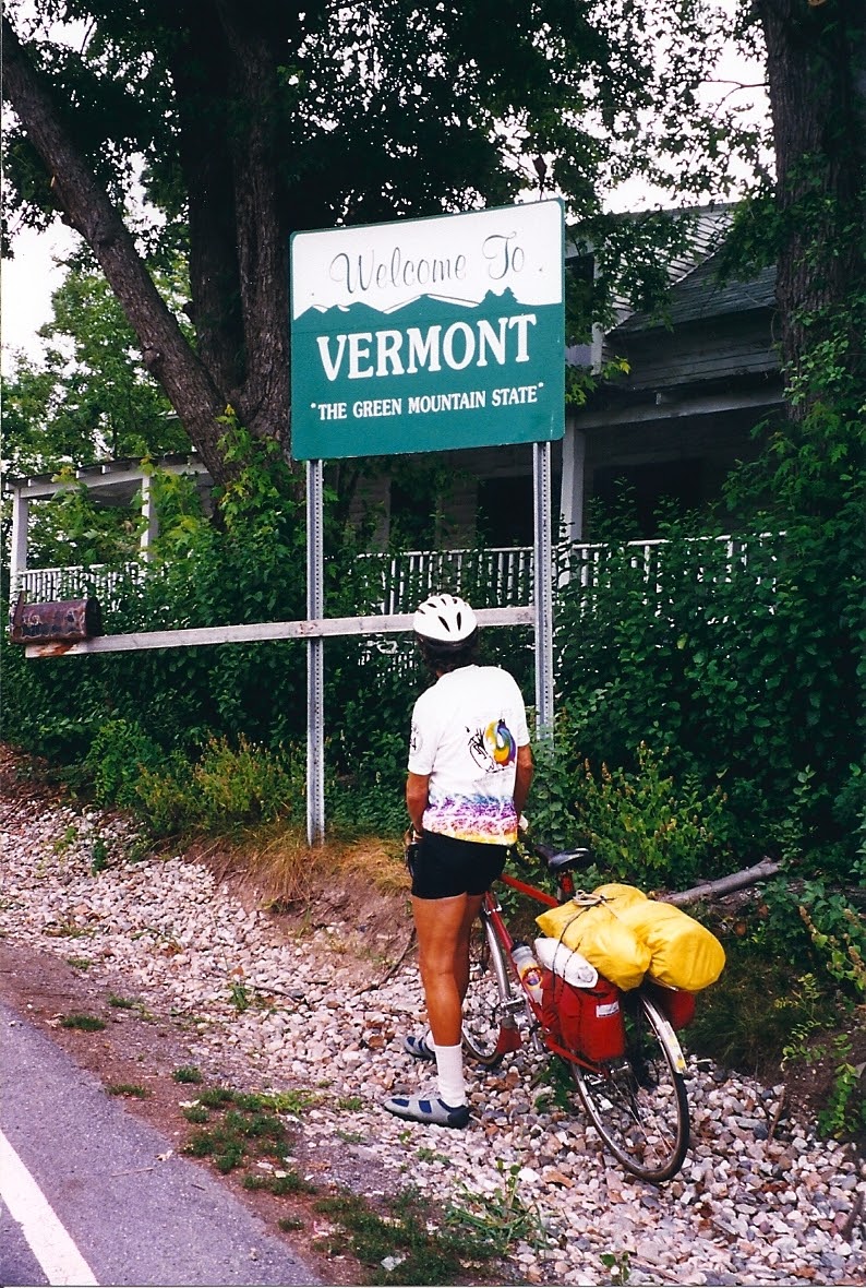 Tom or his touring bicycle photographed at the Vermont state line or state landmark.